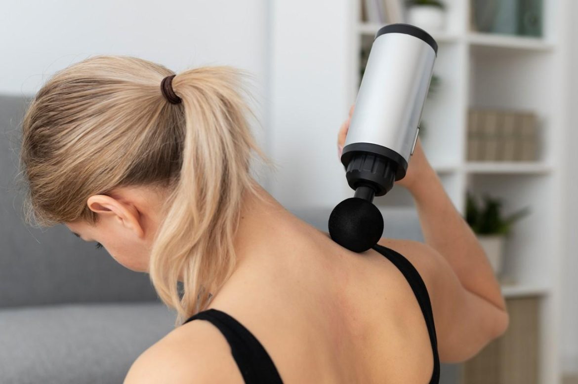 Femme appliquant un pistolet sur l'épaule pour illustrer le massage par percussion fonctionnement et précautions.